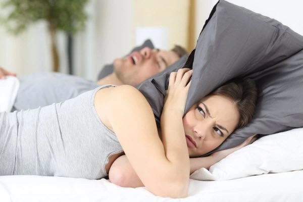 A woman covering her ears with a pillow