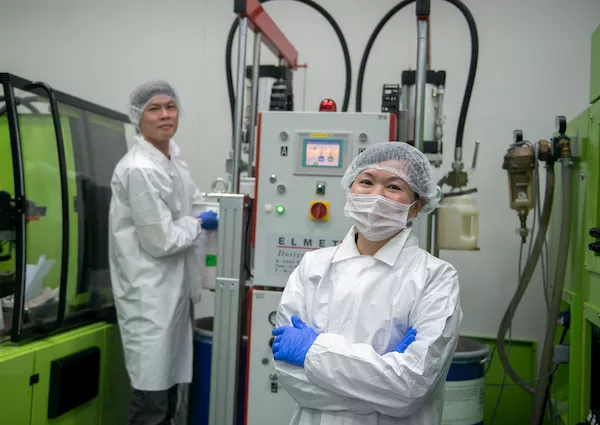 Man and woman wearing a laboratory coat and hairnet inside a laboratory
