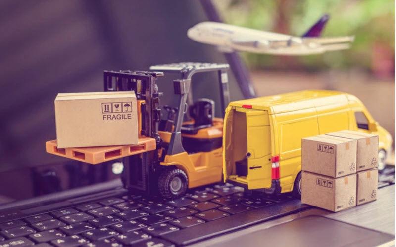 Miniature forklift truck with boxes and Yellow van on laptop